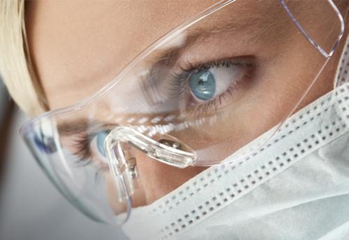 Frau trägt UV-Augenschutz von Dymax mit einer medizinischen Gesichtsmaske